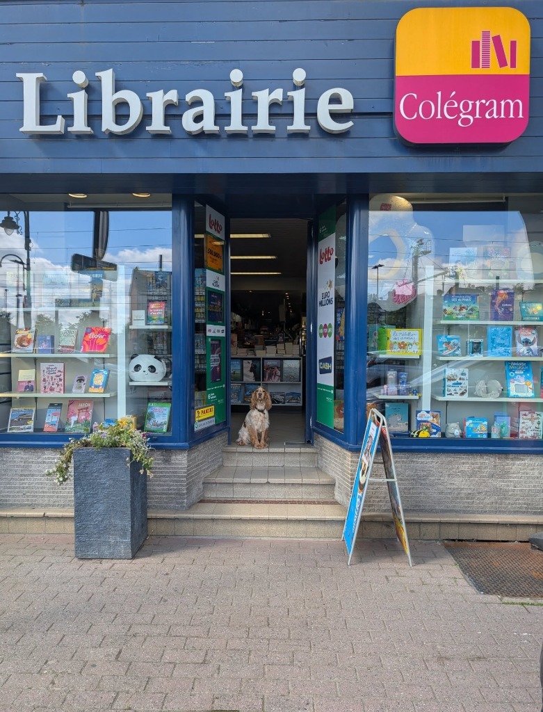 Façade de la Librairie Colégram à Gembloux avec son enseigne bleue et sa mascotte
